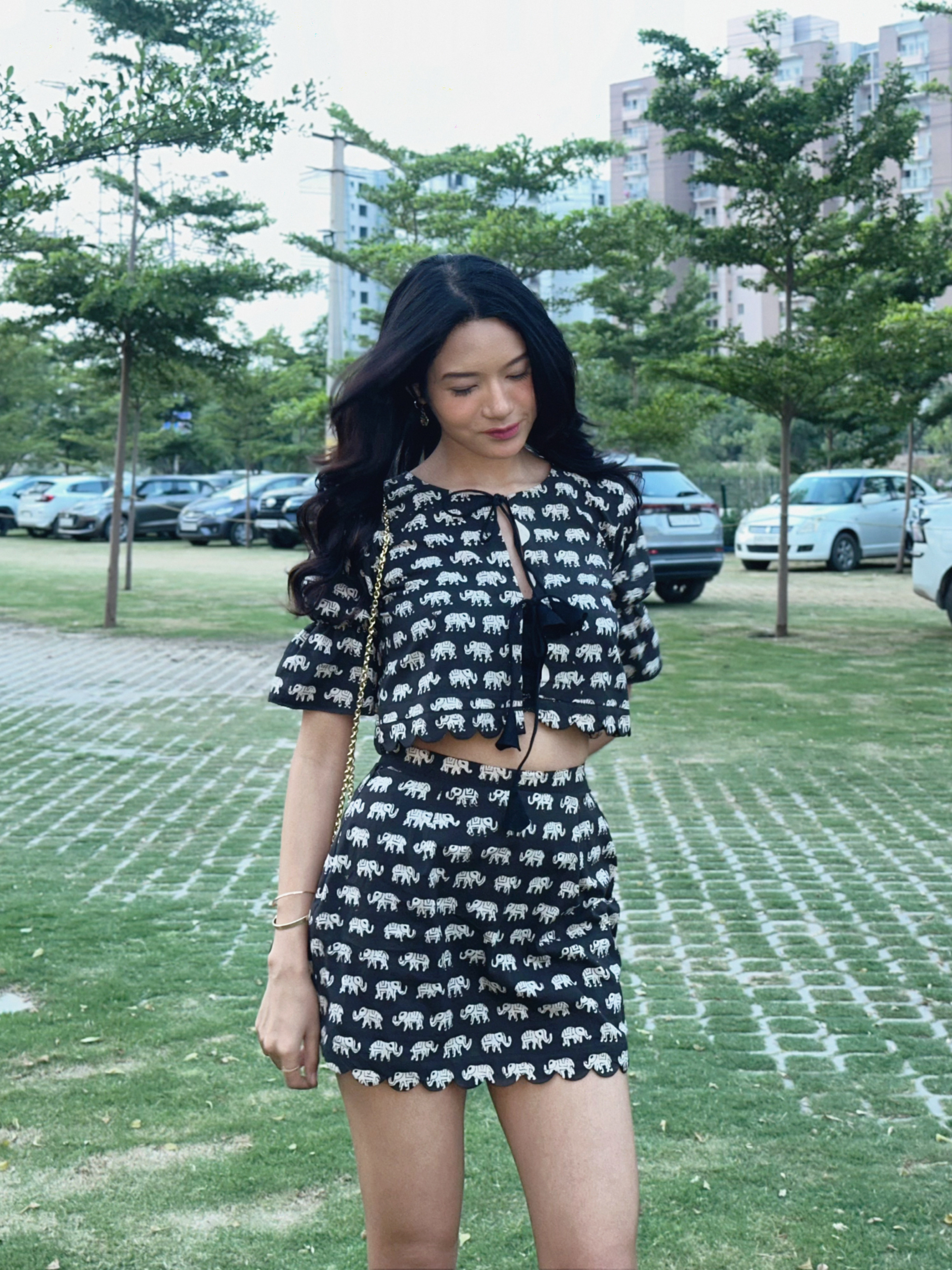 Jelina Derapi in a black elephant-print crop top and skirt co-ord, outdoors in natural light