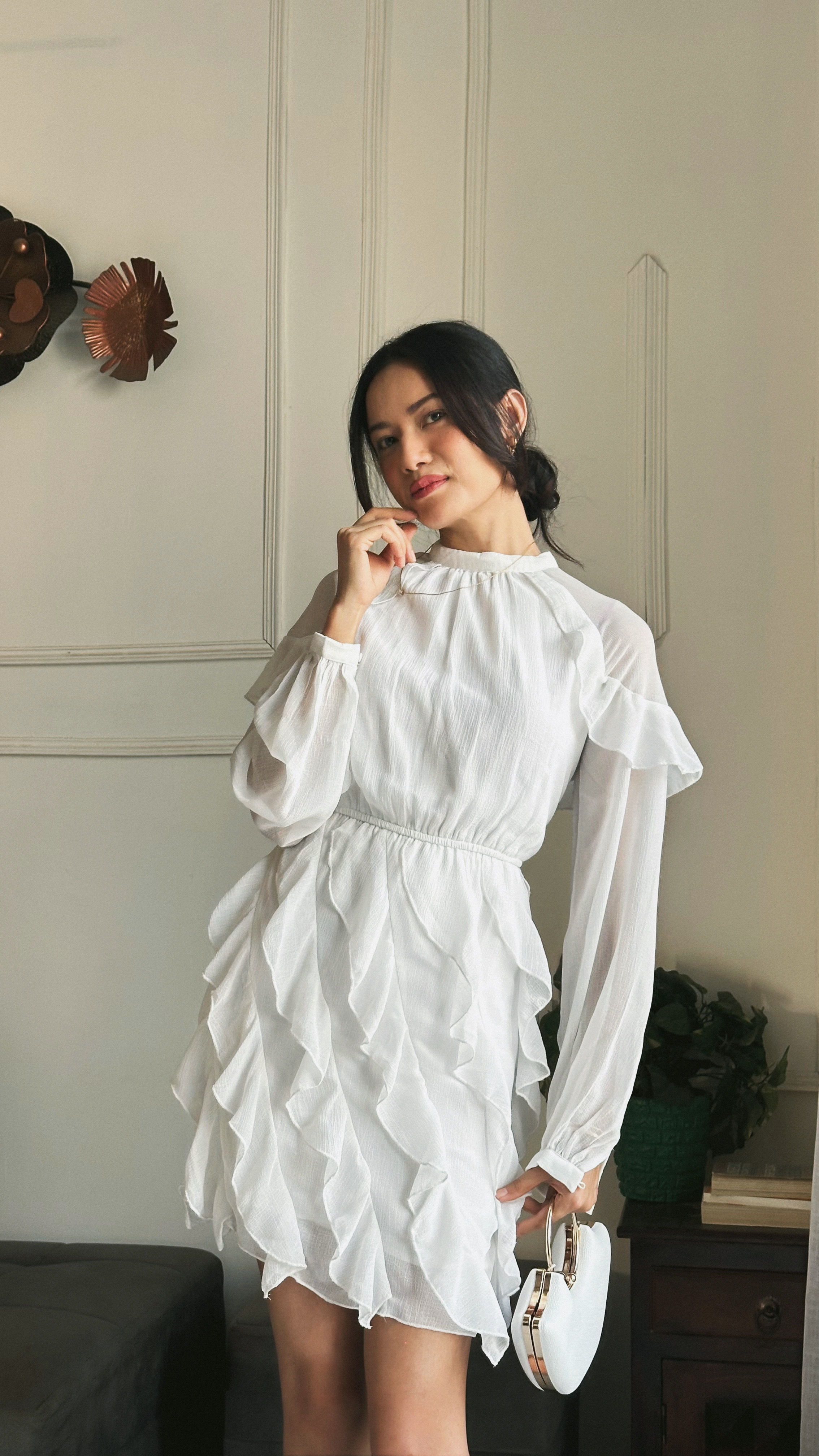 Jelina Derapi in a white ruffled dress, styled indoor lifestyle portrait at home