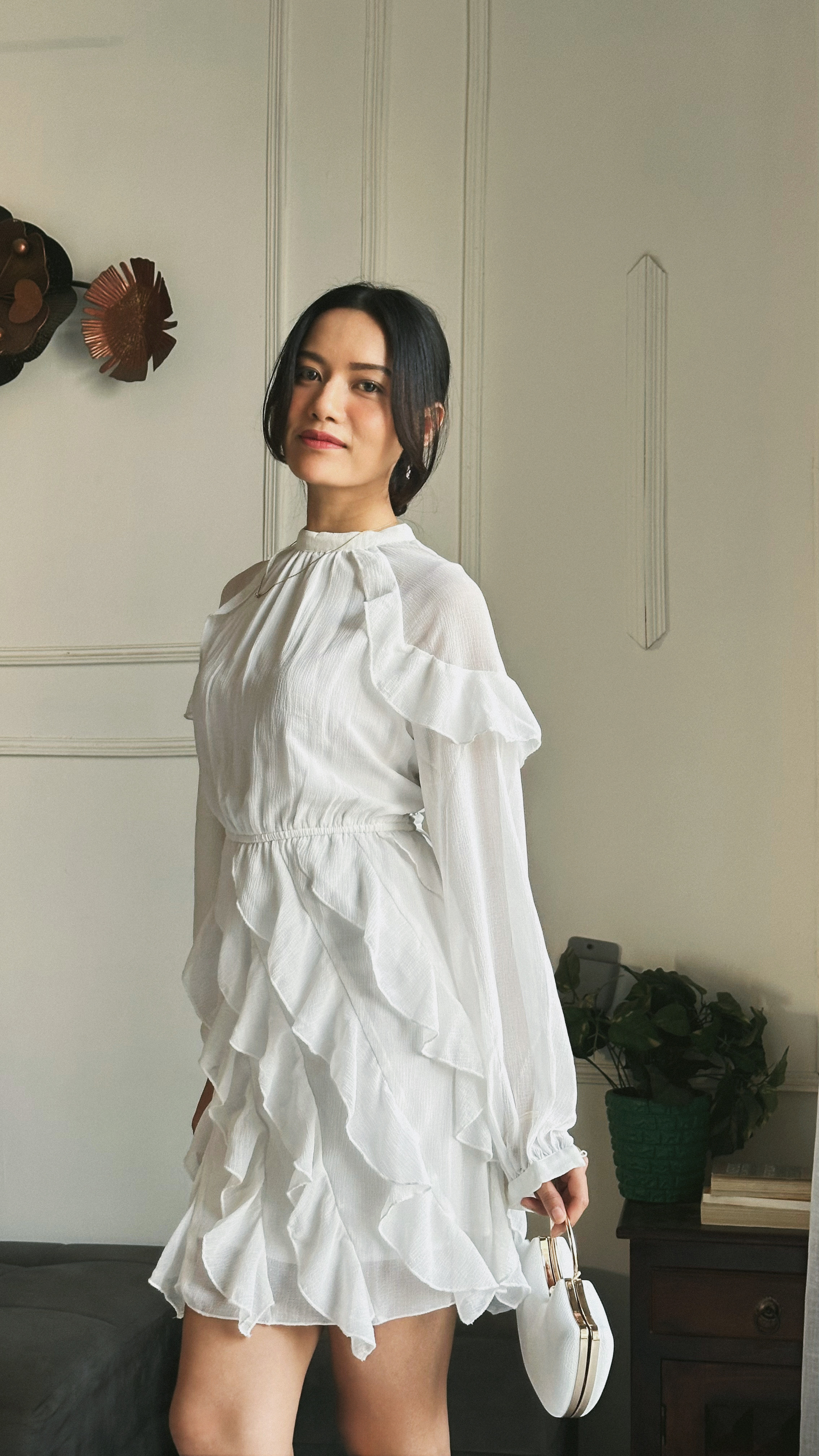Jelina Derapi, fashion stylist and content creator, in a white ruffled dress with a white top-handle bag, editorial portrait